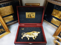 Златен бик в подаръчна кутия и златна банкнота 100 долара